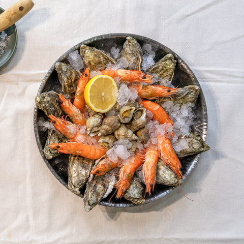Seafood platter from above with oysters, prawns, whelks and lemon on crushed ice